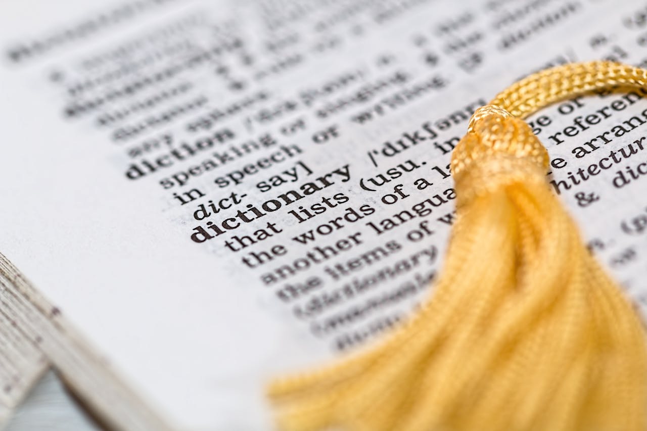 Close-up image of a dictionary page focused on the word dictionary with a yellow tassel.