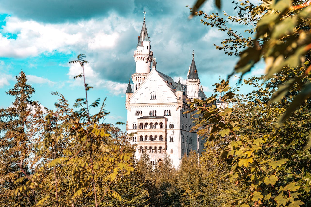 A stunning view of Neuschwanstein Castle amidst vibrant trees, under a clear blue sky.